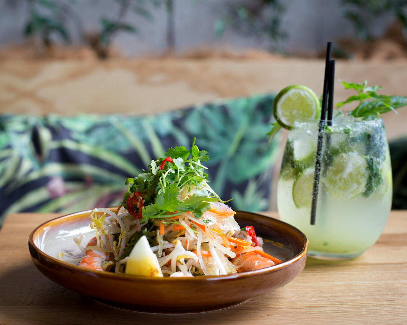 A delicate noodle dish stands alongside a delicious looking cocktail.