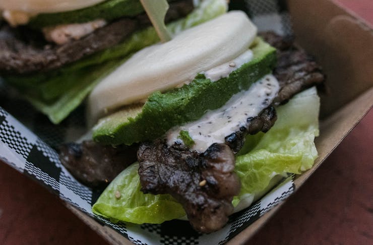 A close up of a beef short tip bao with lettuce and avocado