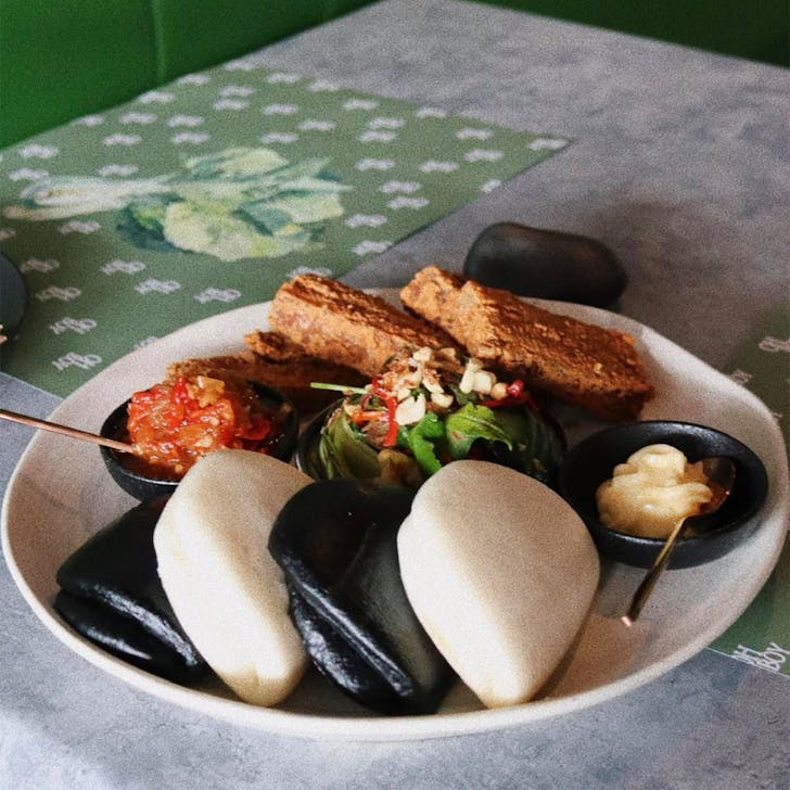 a plate of bao buns with fillings and suace