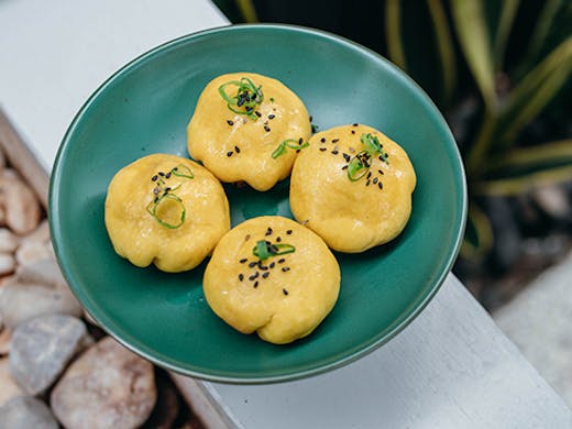 a plate of 4 yellow bao dumplings
