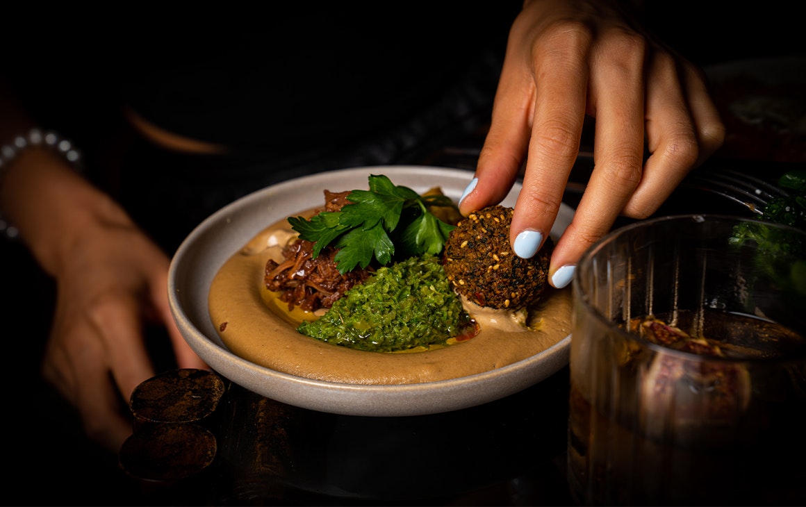 falafel being dipped in hummus