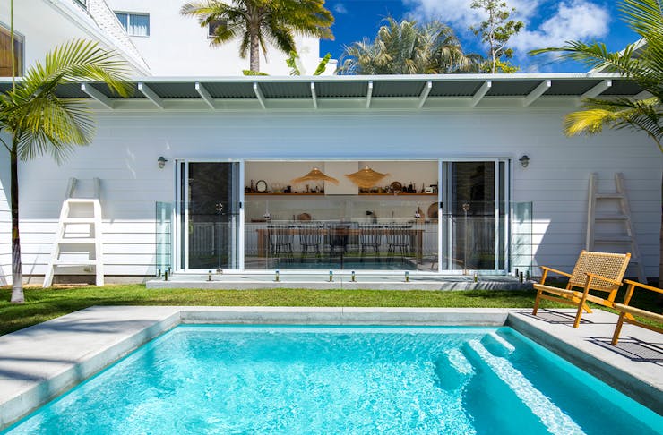 a white beach house with a pool in front of it