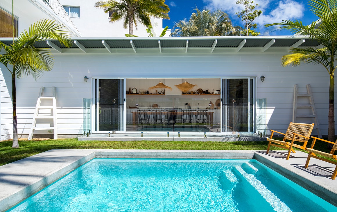a white beach house with a pool in front of it