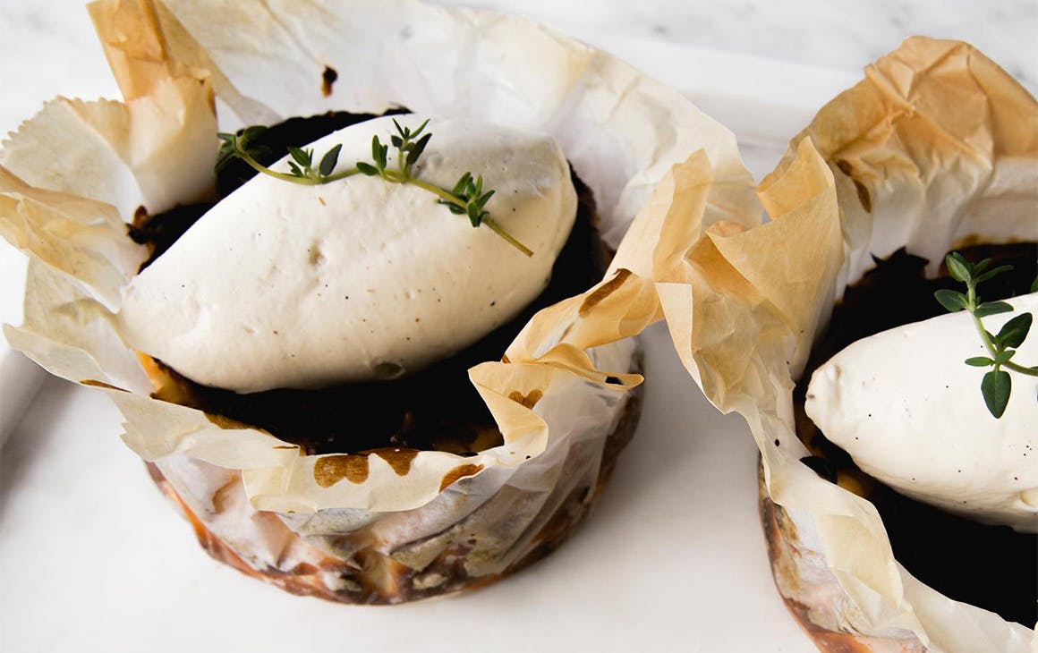 a paper wrapped basque cheesecake with a dollop of cream on top