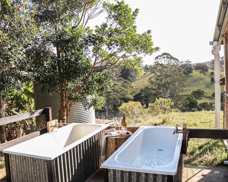 A view of the twin outdoor baths overlooking the garden at Hidden Creek Cabin Airbnb near Brisbane, Queensland