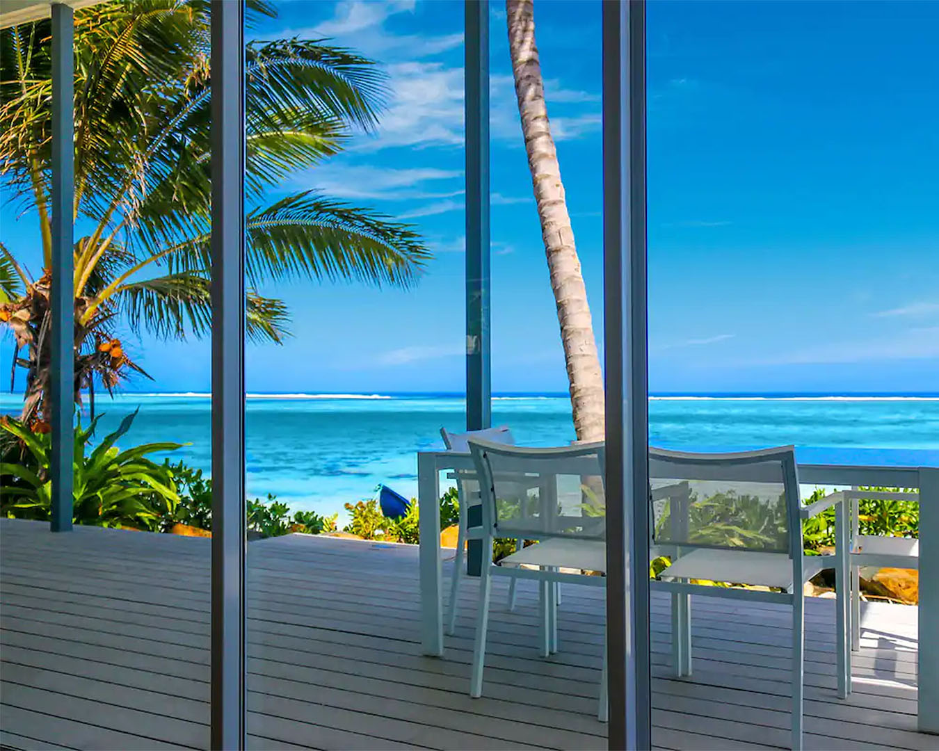 A view through patio doors of an absolutely stunning blue lagoon at this beach vibe executive villa, one of the best airbnbs in Raro.