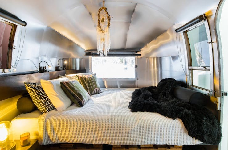 A made queen size bed inside a cosy Airstream in Noosa.