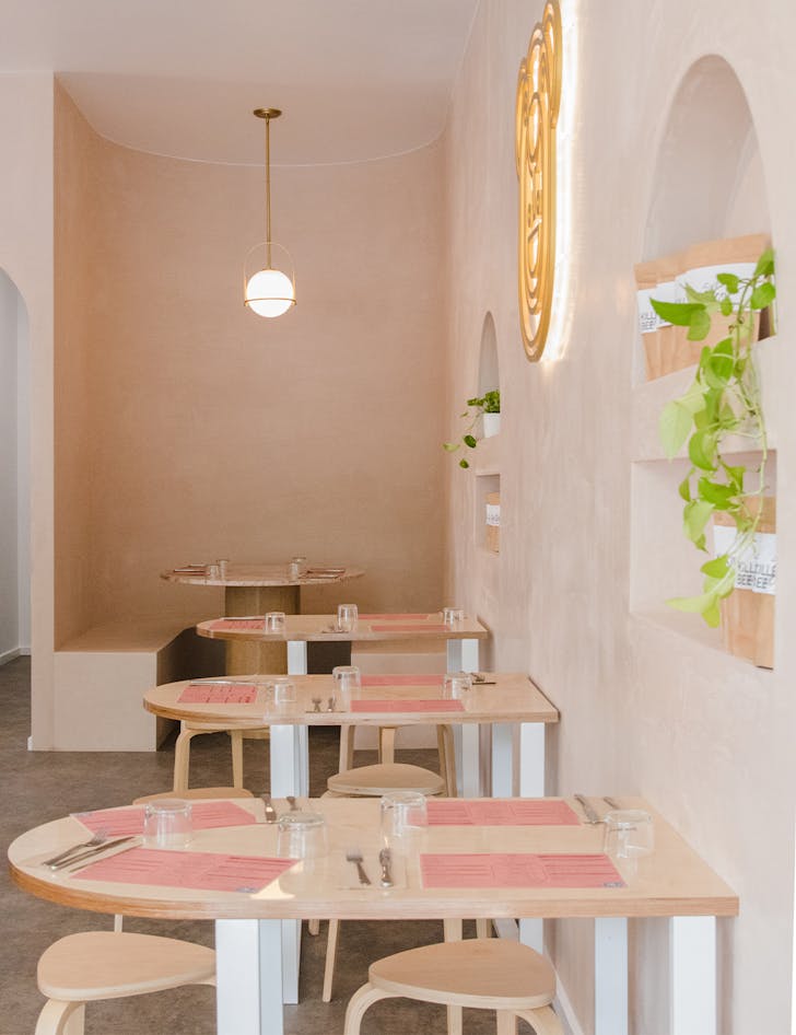 interior of a pink cafe, with low tables and a curved booth