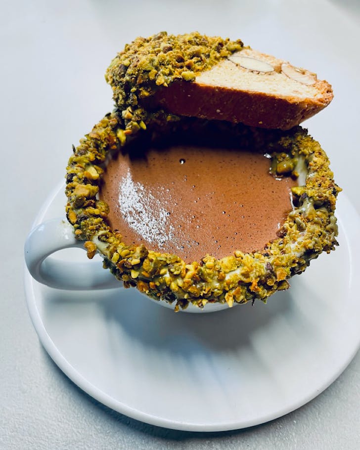 A rich dark chocolate drink with a pistachio-choc rim and biscotti decorated in the same fashion. 