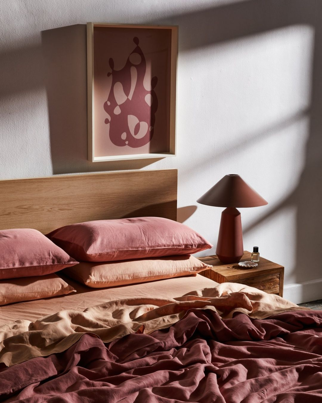 A sunkissed bed is adorned with a rose-hued linen sheet set from Bed Threads
