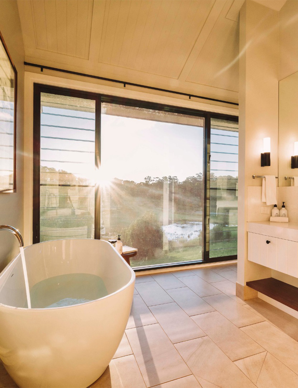 a bath in front of a floor-to-ceiling window in a cabin at beechmont estate