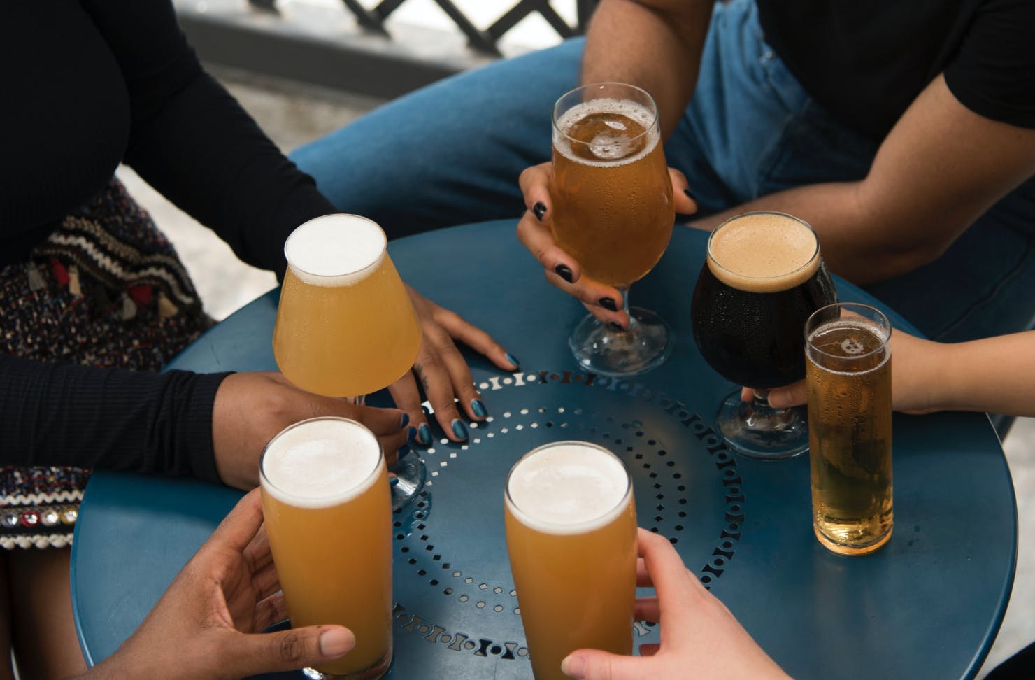 A group of people holding different types of beer handle