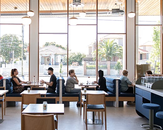 A cafe with floor to ceiling windows on a sunny day.