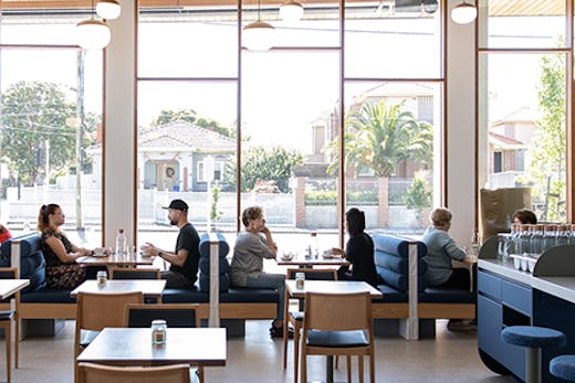 A cafe with floor to ceiling windows on a sunny day.