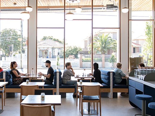 A cafe with floor to ceiling windows on a sunny day.