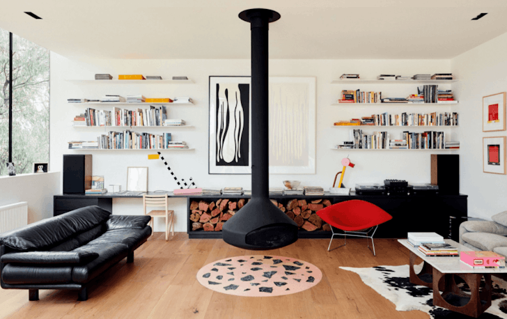 A black rounded fireplace hangs from the roof in the centre of a Airbnb Melbourne living room with a rug underneath.
