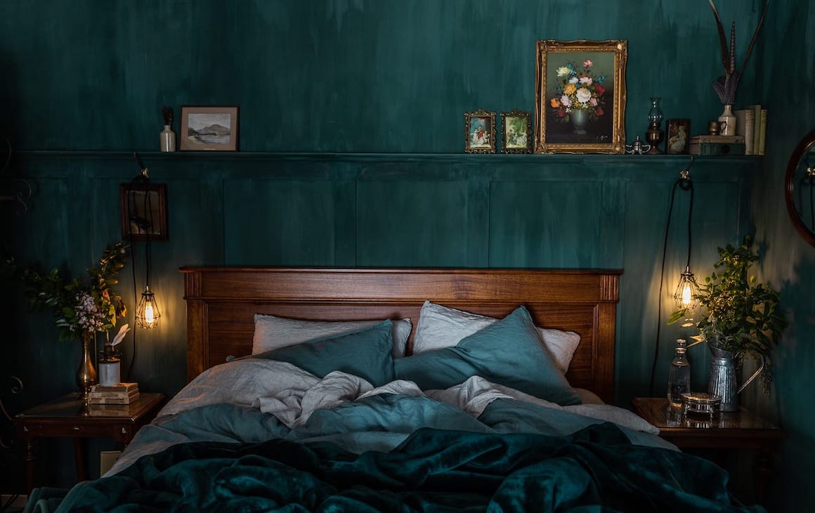 a moody green-hued bedroom