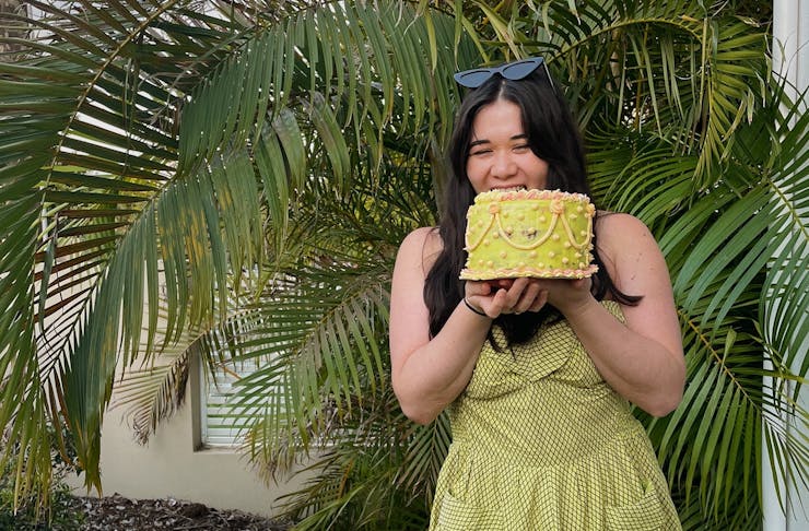A person in a green dress holding a bright green cake