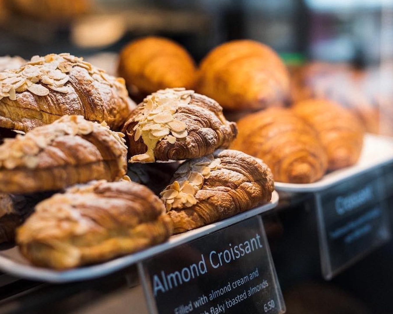 almond croissants stacked up in a display cabinet