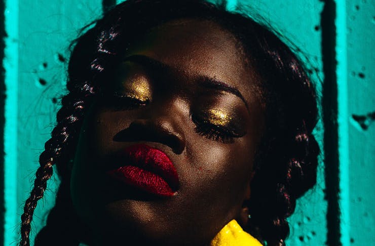 A woman wearing gold eye shadow and red lipstick. 