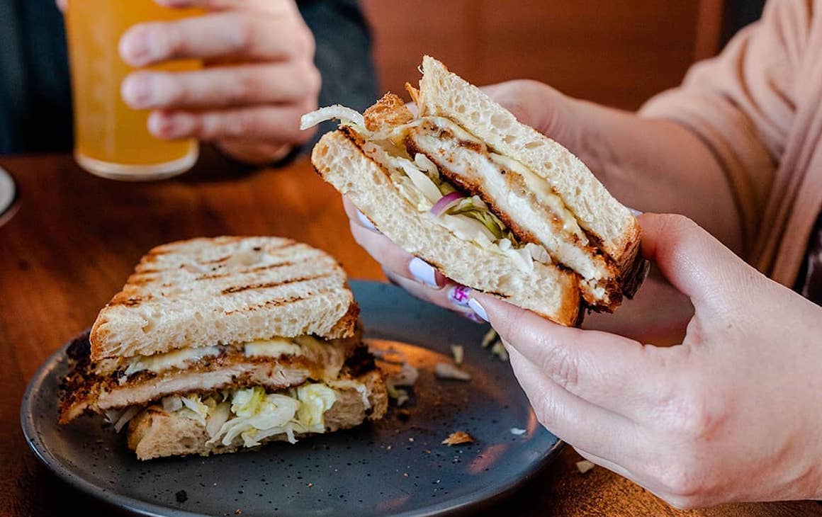 person holding half of a chicken schnitzel sandwich from Bark in Subiaco