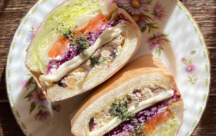 a chicken sandwich cut in half with lots of salad
