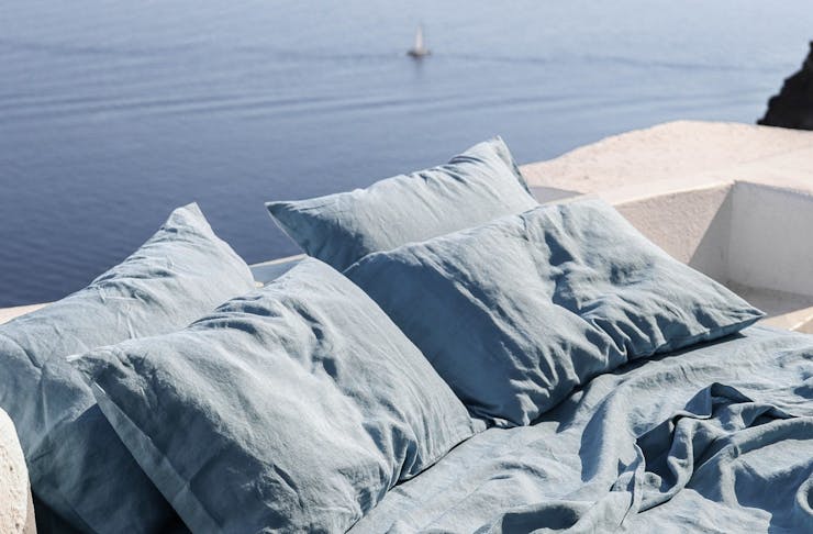 Blue linen sheets with the ocean in the background. 