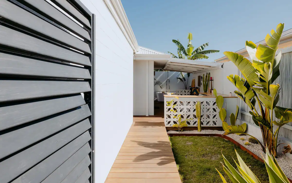 view of the house with lots of leafy green plants, a bar and bathtub in the distance