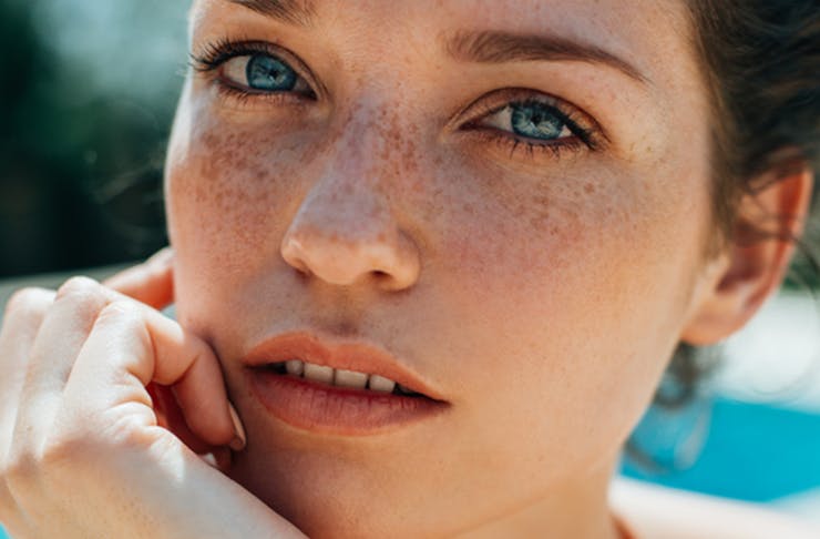 A close-up of a pretty woman with blue eyes and freckles.