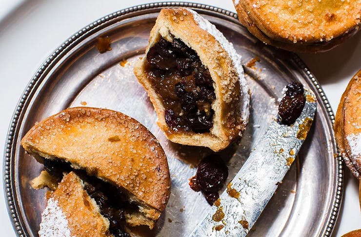 A silver plate with a Christmas fruit mince pie cut in half. 