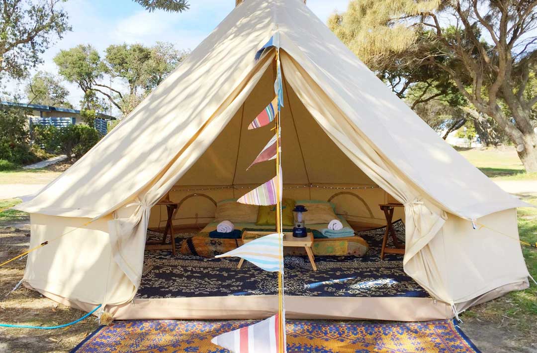 The opening to a glamping tent in Victoria with rugs and a bed set up.