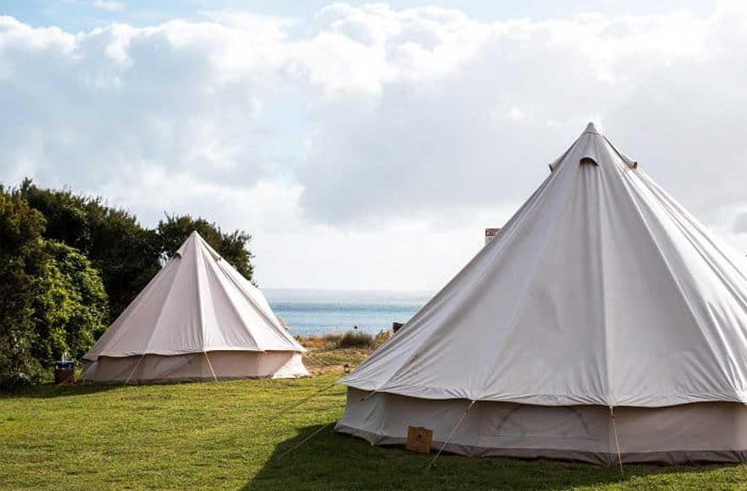 Two glamping Victoria tents set up by the ocean. 
