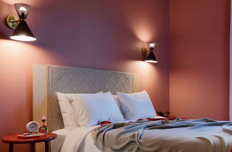 a bed in a pink-hued hotel room