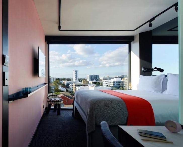 a contemporary hotel room with pink-hued walls and large window