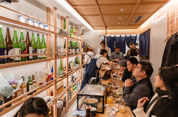 Sake bottles line the wall at Nomidokoro Indigo Japanese restaurant in Sydney