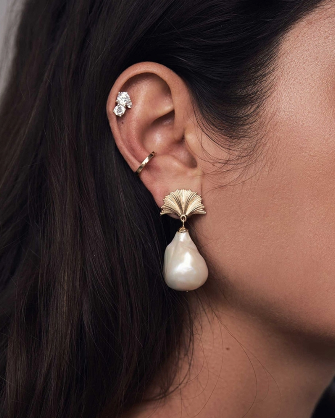 Someone wears a pearl and stud earrings from Meadowlark.