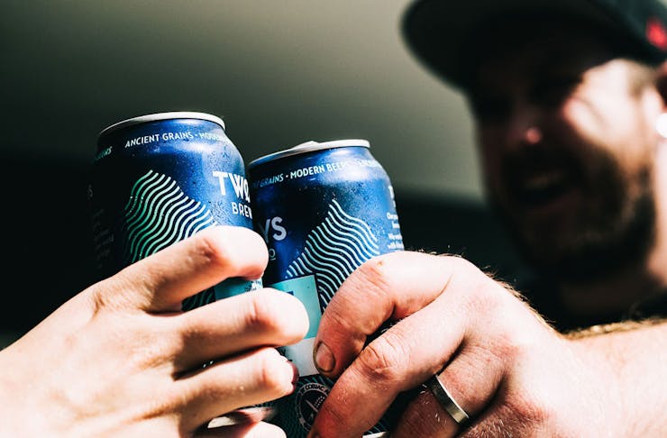 Two people cheers-ing with blue tinnies.