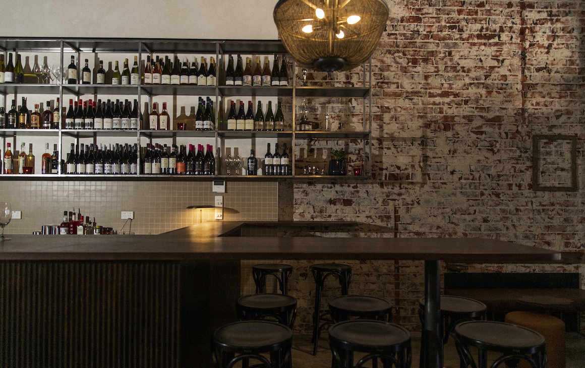 a dimly lit bar lined with wine bottles
