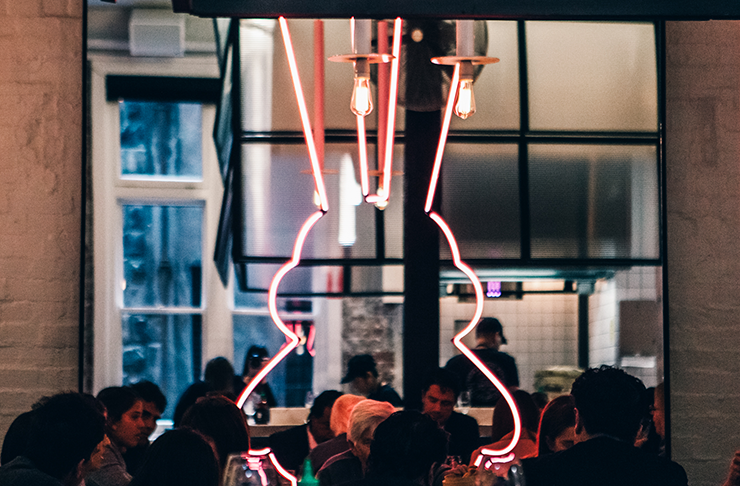 A neon light shaped line a rabbit in a dining room buzzing with people at Chin Chin, one of the best restaurants Melbourne has on offer for 2024.