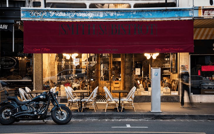 Several outdoor dining sets and a motorbike sit outside one of the best French restaurants in Melbourne, Smith St Bistro.