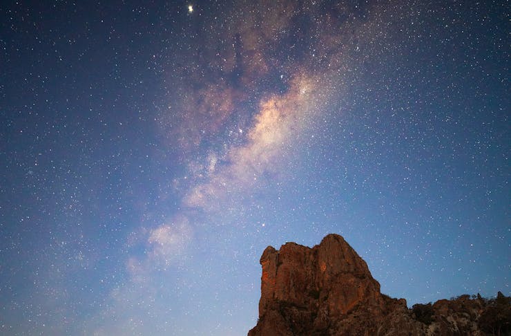 Stars lighting up the night sky over the Breadknife rock formation in Warrumbungle National Park.