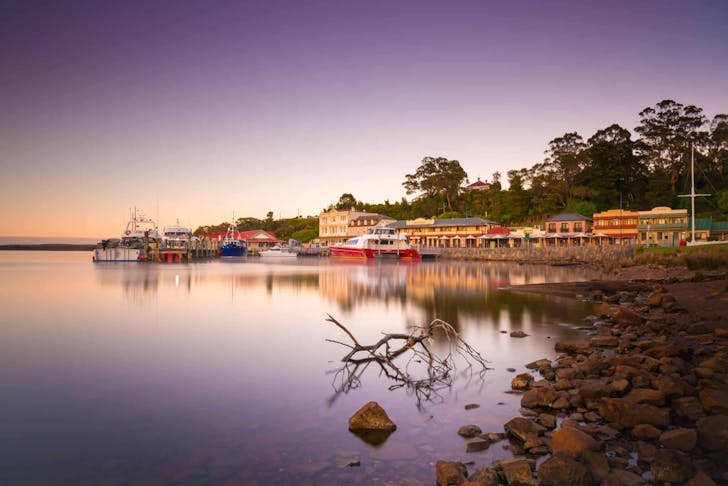 A stunning, purple and pink hued sunset shot of the town of Strahan in Tasmania.