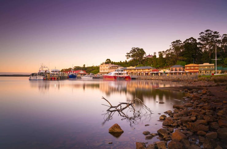 A stunning, purple and pink hued sunset shot of the town of Strahan in Tasmania.