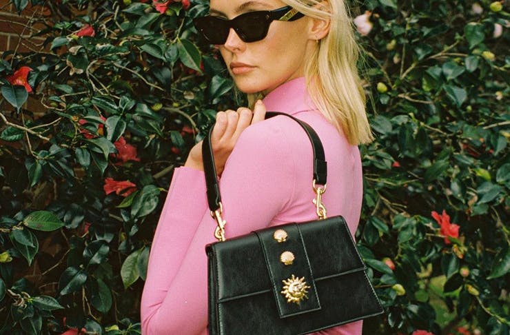A model holding a black Poppy Lissiman vegan handbag. 