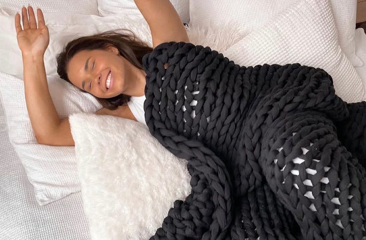 A woman sleeping with a black weighted blanket 