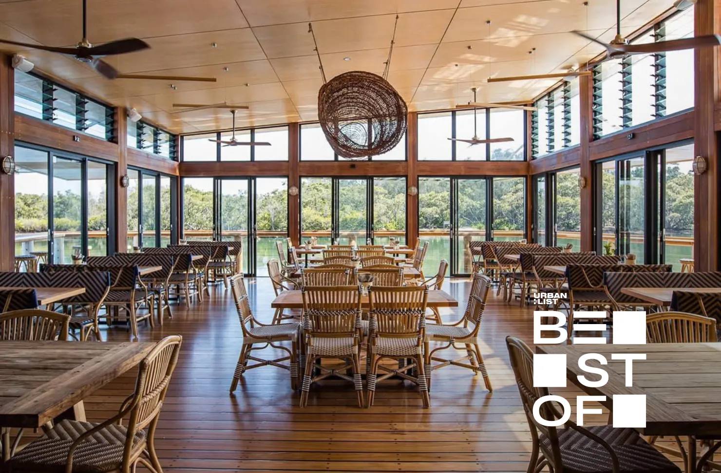 Spacious waterfront restaurant with timber interiors, wicker pendant lighting and floor-to-ceiling windows overlooking mangroves and Brisbane Water on the Central Coast.