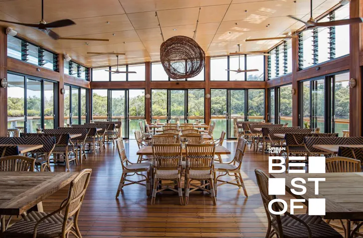 Spacious waterfront restaurant with timber interiors, wicker pendant lighting and floor-to-ceiling windows overlooking mangroves and Brisbane Water on the Central Coast.