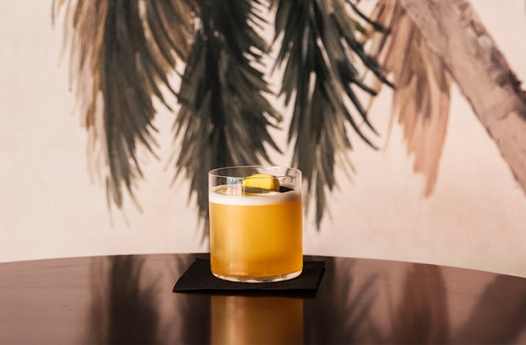 a yellow cocktail sitting on a curved table