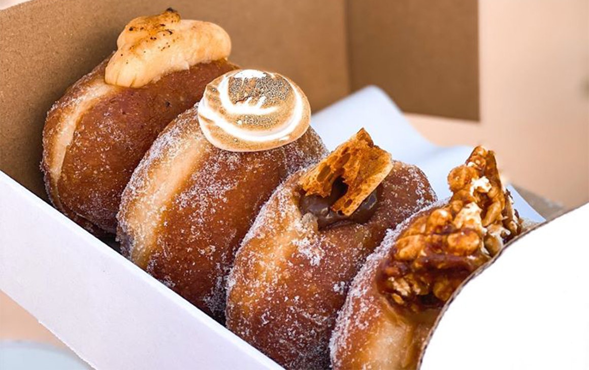 Several filled doughnuts in a cardboard box