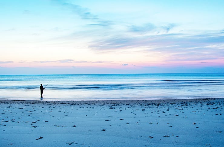 Perth beach at sunset with a person fishing.